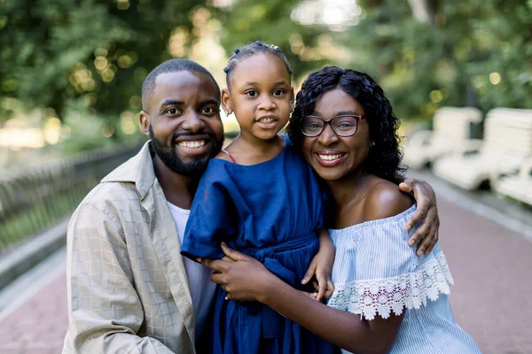 子供の娘と明るい若いアフリカのカップルの肖像画を閉じます,幸せな笑顔でカメラにポーズ,公園で一緒に彼らの時間を楽しみながら、 — ストック写真
