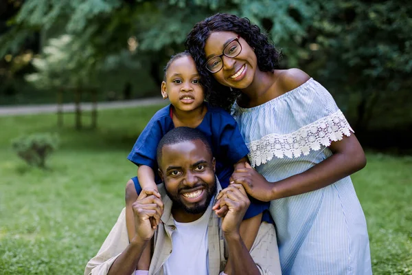 Família recreação ao ar livre, família feliz no conceito de amor. Família africana atraente alegre que joga no parque. Mãe, pai e filha fazendo piquenique no parque de verão — Fotografia de Stock