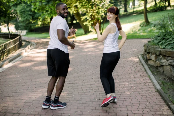 Casal jovem, homem africano e mulher caucasiana, se preparando para corrida e treinamento de fitness ao ar livre no parque da cidade. Desporto, exercício, fitness, treino. Estilo de vida saudável . — Fotografia de Stock