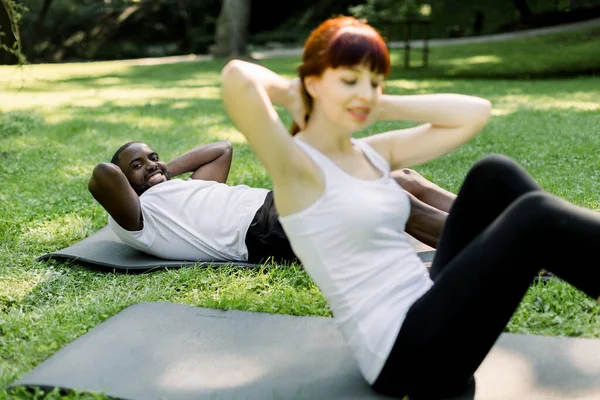 Instrutora de fitness feminina se exercitando fazendo sit-ups no tapete de ioga fora no parque de verão verde — Fotografia de Stock