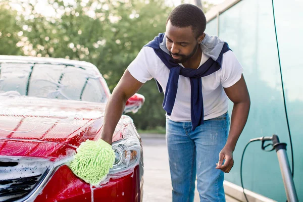 Közelkép a kéz zöld ecset mosás piros autó — Stock Fotó
