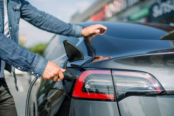 Horizontal aufgenommene Nahaufnahme eines Mannes, der sich darauf vorbereitet, ein Elektroauto an einer Ladestation in der Stadt aufzuladen. Kopierraum. Konzept Öko-Elektroauto — Stockfoto