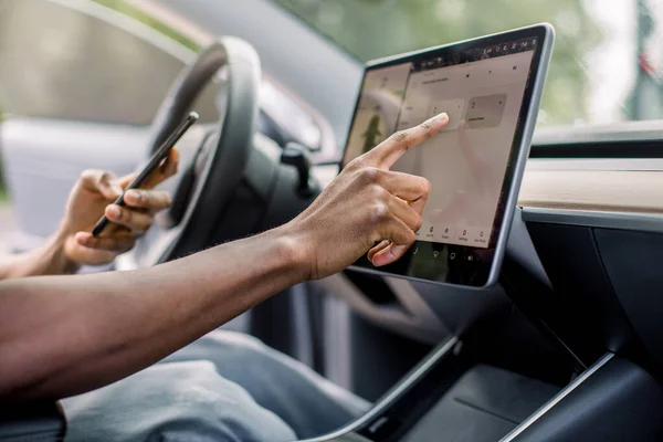 무인 운전 자동차 시스템은 인간의 개입이 없습니다. 최신 무인 자동차에서 스마트폰과 터치스크린을 사용하여 인터넷을 검색하는 아프리카 남성 운전자의 사진이 근접 해 있다. — 스톡 사진