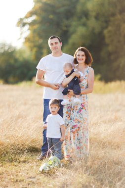 Çocuklarla dolu bir aile gün batımında yaz tarlasında yürüyorlar. Baba, anne ve iki çocuk yaz tarlasında eğleniyorlar. İnsanlar, aile günü ve yaşam tarzı konsepti
