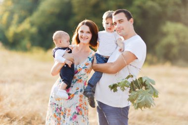 Çocuklarla dolu bir aile gün batımında yaz tarlasında yürüyorlar. Baba, anne ve iki çocuk yaz tarlasında eğleniyorlar. İnsanlar, aile günü ve yaşam tarzı konsepti