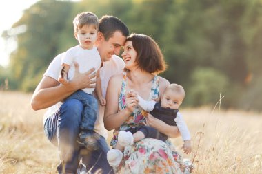 Çocuklarla dolu bir aile gün batımında yaz tarlasında yürüyorlar. Baba, anne ve iki çocuk yaz tarlasında eğleniyorlar. İnsanlar, aile günü ve yaşam tarzı konsepti