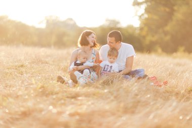 Çocuklarla dolu bir aile gün batımında yaz tarlasında yürüyorlar. Baba, anne ve iki çocuk yaz tarlasında eğleniyorlar. İnsanlar, aile günü ve yaşam tarzı konsepti