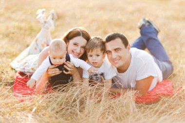 Çocuklarla dolu bir aile gün batımında yaz tarlasında yürüyorlar. Baba, anne ve iki çocuk yaz tarlasında eğleniyorlar. İnsanlar, aile günü ve yaşam tarzı konsepti