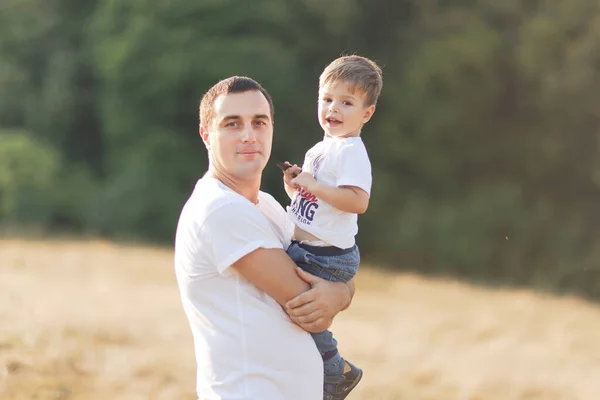 Família com crianças andando ao ar livre no campo de verão ao pôr do sol. O pai e o filho a divertirem-se no campo de verão. Pessoas, dia de família e conceito de estilo de vida — Fotografia de Stock