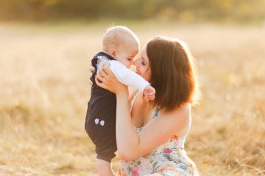 Çocuklarla dolu bir aile gün batımında yaz tarlasında yürüyorlar. Güzel genç anne ve küçük oğlu çimlerin üzerinde oturmuş, yaz tarlasında eğleniyorlar. İnsanlar, aile günü ve yaşam tarzı konsepti