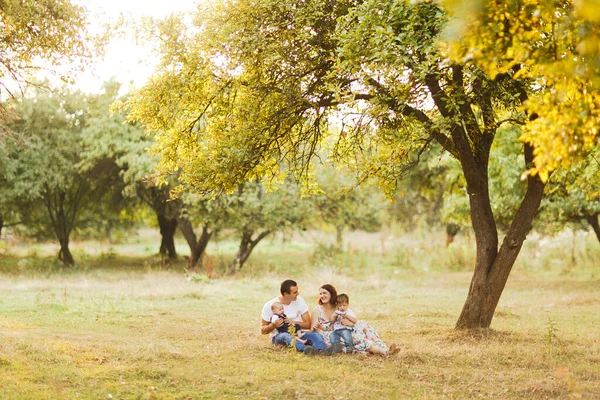 Família com crianças andando ao ar livre no campo de verão ao pôr do sol. Pai, mãe e dois filhos filhos se divertindo no campo de verão. Pessoas, dia de família e conceito de estilo de vida — Fotografia de Stock