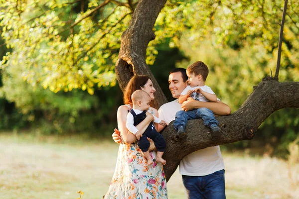 Família com crianças andando ao ar livre no campo de verão ao pôr do sol. Pai, mãe e dois filhos filhos se divertindo no campo de verão. Pessoas, dia de família e conceito de estilo de vida — Fotografia de Stock