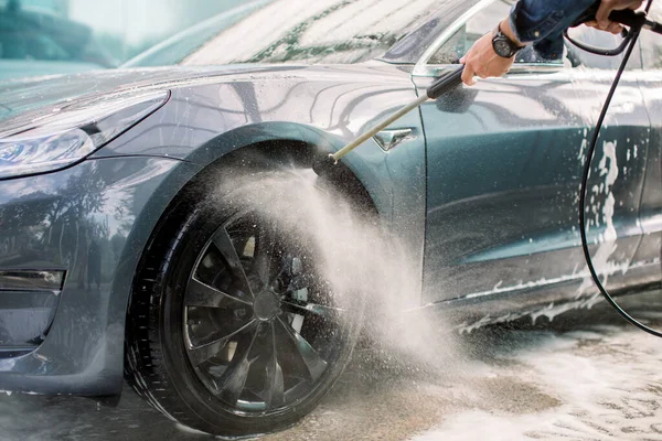Dışarıda araba yıkama. Sabun ve yüksek basınçlı suyla araba yıkama. Araba yıkama istasyonunda köpük ve yüksek basınçlı su jeti ile tekerlek alaşımı temizliği. Yıkama jantları