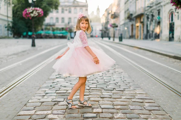 Menina em vestido rosa e flor em seu cabelo andando pelas ruas da cidade velha em Lviv, Ucrânia — Fotografia de Stock