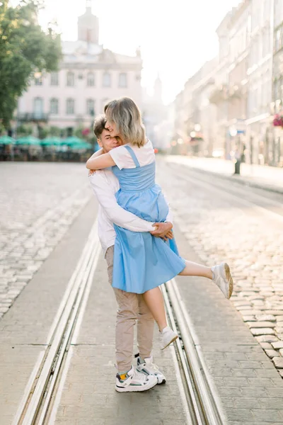 Birbirlerine aşık sevimli bir çift, güneşli bir günde tramvay yolunda yürürken eğleniyorlar. Yakışıklı genç kız arkadaşını mavi elbisesiyle elinde tutuyor.
