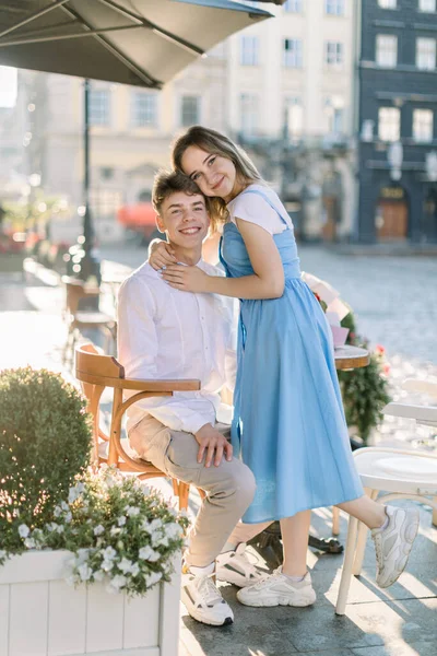 Summer holidays, dating and relationships concept. Young couple in love, hugging each other while sitting in outdoor cafe in old European city, smiling to camera — Stock Photo, Image