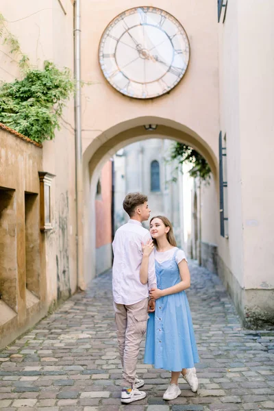 Retrato da cidade ao ar livre de casal feliz no amor, namorado bonito e jovem atraente em vestido azul, andando juntos na bela cidade europeia, de mãos dadas e sorrindo — Fotografia de Stock