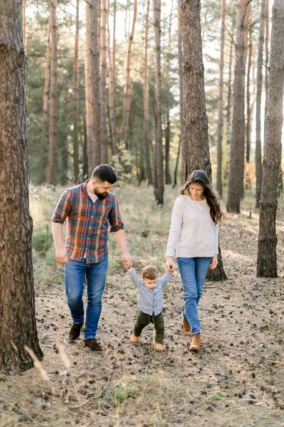 Retrato ao ar livre de uma família feliz de três pessoas, mãe, pai, menino criança, andando fora na bela floresta de pinheiros em um dia de outono. Conceito de família feliz — Fotografia de Stock