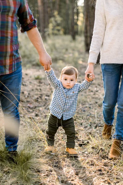 Sonbahar parkında ya da ormanda oğluyla el ele tutuşan genç ebeveynlerin görüntüsü. Sonbahar açık hava portresi. Aile, ebeveynlik ve insan konsepti — Stok fotoğraf