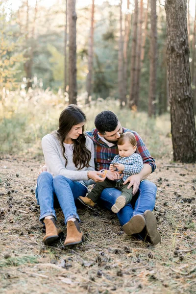 Imagem de pais encantadores com filho pequeno, no parque de outono ou na floresta, sentados juntos e desfrutando de seu tempo em família, brincando ao ar livre. Família feliz no outono natureza — Fotografia de Stock