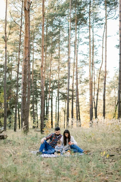 Lifestyle portrait de famille en plein air de jeunes parents avec un petit fils enfant, s'amuser ensemble, tout en étant assis sur la couverture dans la belle forêt d'automne à la journée ensoleillée — Photo