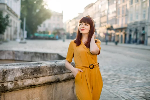 Retrato de bela mulher bonita sorridente em roupas amarelas na moda, posando para câmera em uma rua da antiga cidade europeia. Pessoas, retrato da cidade e conceito de estilo de vida — Fotografia de Stock