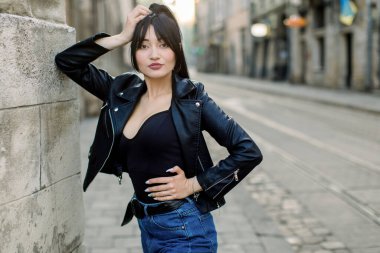 Ceketli ve güneş gözlüklü moda kadını sokakta yürüyor, şehir manzarası. Boşluğu kopyala.