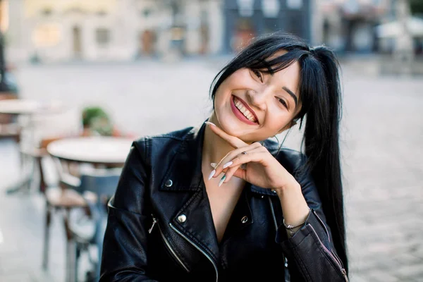 People, races and city life concept. Cafe city lifestyle portrait of young pretty mixed raced Asian Caucasian model woman, sitting outdoor in trendy urban cafe and smiling to camera