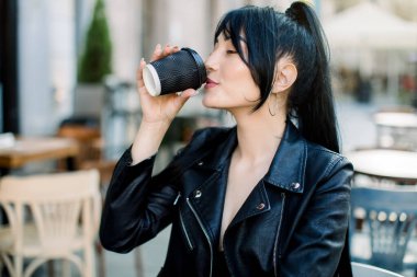 Genç, güzel, melez, esmer bir kadının portresi. Kahvesini yudumluyor, dışarıdaki kafede oturuyor. Güneşli bir sabahta, şehrin eski bir sokağında. Kahve aşığı kavramı