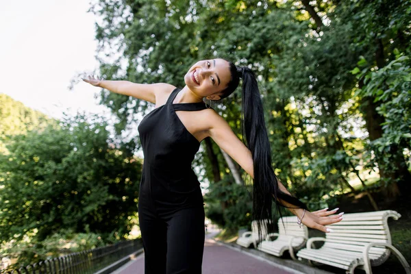 Estilo de vida retrato de bela mulher asiática alegre animado em moda desgaste preto no parque ao ar livre, se divertindo e emoções felizes, andando com os braços estendidos. Pessoas, conceito de emoções — Fotografia de Stock