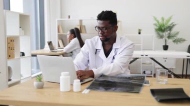 Erkek Afrikalı sağlık uzmanı röntgen sonuçlarını modern tıbbi çalışma alanında analiz ediyor. Olay yeri incelemeleri tıbbi analiz konsepti, profesyonel sağlık hizmetleri, hasta teşhisleri