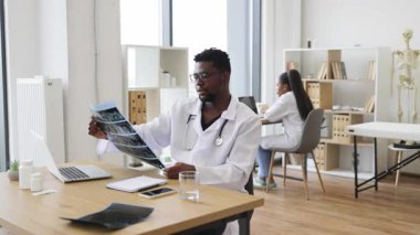 Erkek Afrikalı sağlık uzmanı röntgen sonuçlarını modern tıbbi çalışma alanında analiz ediyor. Olay yeri incelemeleri tıbbi analiz konsepti, profesyonel sağlık hizmetleri, hasta teşhisleri