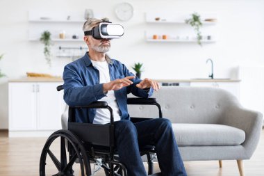 VR kulaklık takan son sınıf öğrencisi tekerlekli sandalyede otururken sanal arayüzü keşfediyor. Yetişkinler için erişilebilirlik, modern teknoloji ve oyun kavramı.