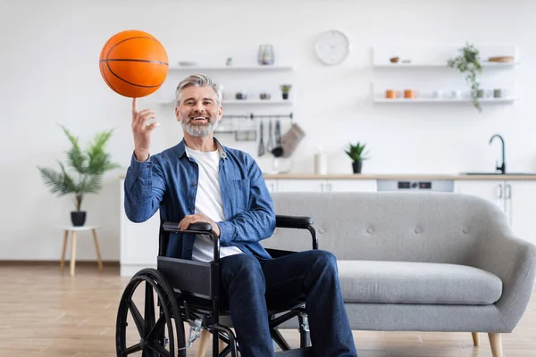 Tekerlekli sandalyedeki son sınıf öğrencisi modern oturma odasında neşeli bir ifadeyle basketbol dönüşü yapıyor.