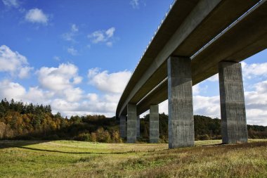 Underneath a new motorway bridge crossing a small valley