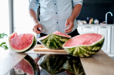 Erkekler el ahşap masa mutfak arka plan, kırmızı ve sulu karpuz kestim