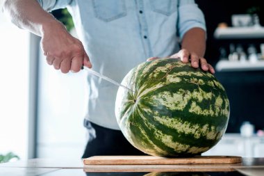 Erkekler el ahşap masa mutfak arka plan, kırmızı ve sulu karpuz kestim