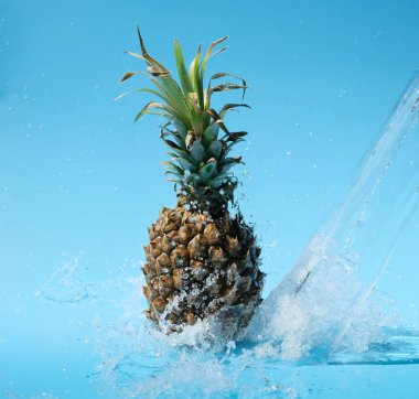 Mavi arka planda su sıçrama ananas
