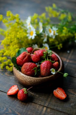 Koyu arka planda sarı çiçekler ile sulu çilek ile Bowl