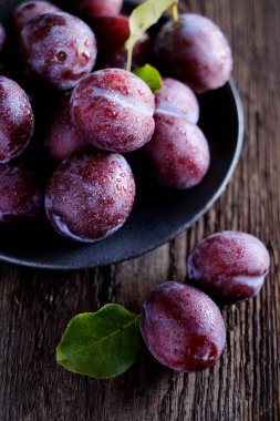 Koyu ahşap masa arka planda taze mor erik