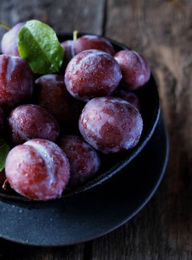 Koyu ahşap masa arka planda taze mor erik