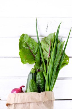 Kağıt paket ahşap beyaz arka plan üzerinde taze yeşil sebzeler ile dolu. Alanı