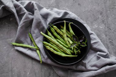 Gri çimento backgound taze yeşil dize fasulye ile Siyah kase