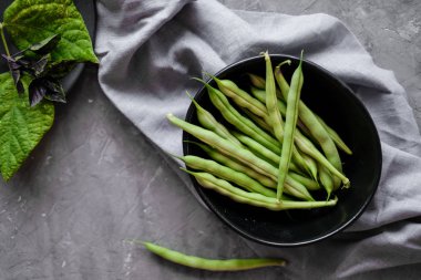Gri çimento backgound taze yeşil dize fasulye ile Siyah kase