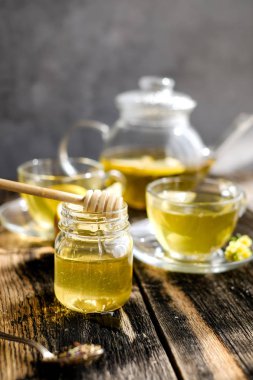 Güneşli gün ışığında cam bardak ve çaydanlık limon ve bal ile bitkisel çay