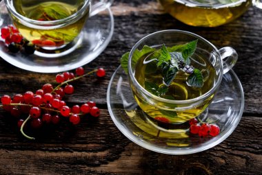 Ahşap masa arka plan üzerinde cam bardak bir çilek ile Yeşil bitkisel çay