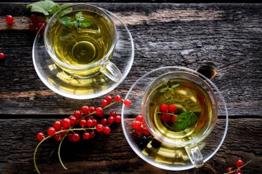 Ahşap masa arka plan üzerinde cam bardak bir çilek ile Yeşil bitkisel çay