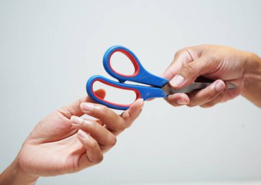 Mavi tutan bir adam el ve kırmızı makas gönderme taraftan çok bir kadın beyaz arka plan üzerinde Kapat.                             