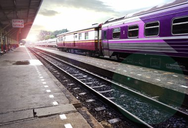Tay tren istasyonunda günbatımı arka plan üzerinde gelen.                          