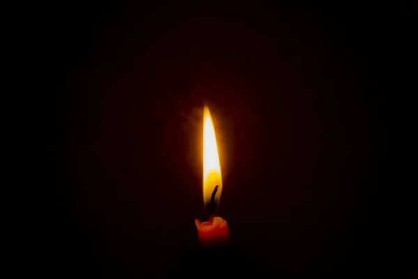 Burning candle in the dark with a dark background. Dark key photo.